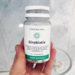 Flacon Girobiotix Serenalpes dans une main dans une salle de bain
